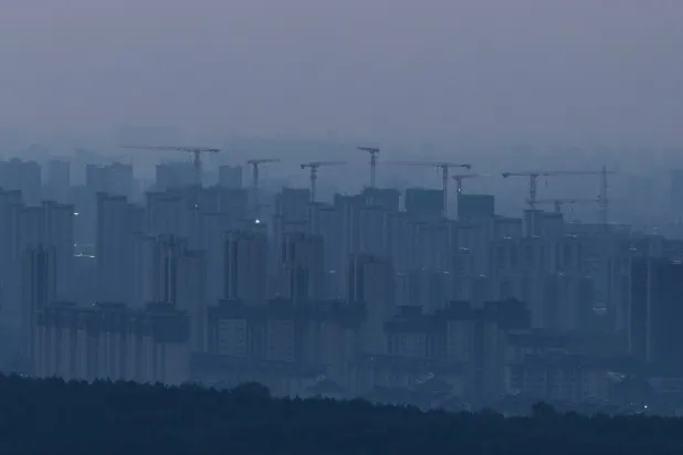 Construction cranes rise above a newly built residential district before sunrise, in Beijing, China, September 3, 2026. REUTERS/Maxim Shemetov