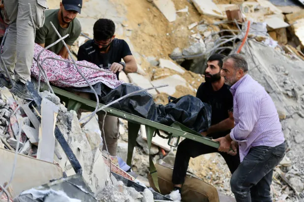 سكان محليون ينقلون جثة ضحية قتلت في غارة إسرائيلية استهدفت منزلاً في بلدة عربصاليم جنوب لبنان (إ.ب.أ)