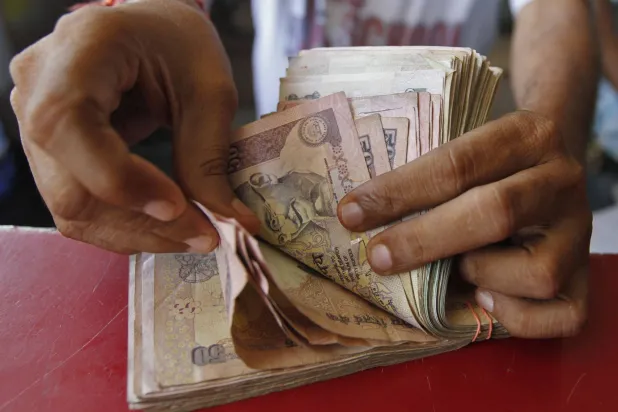 صاحب متجر بقالة يعد أوراق الروبية الهندية في أحمد آباد (رويترز)