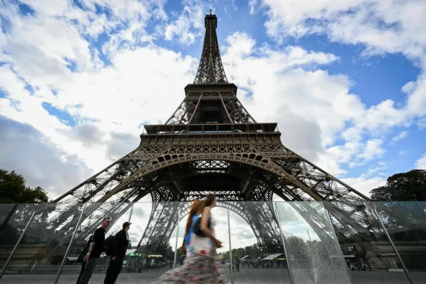 Pedestrians walk past the Eiffel Tower in Paris on September 8, 2026. (Photo by Lou BENOIST / AFP)