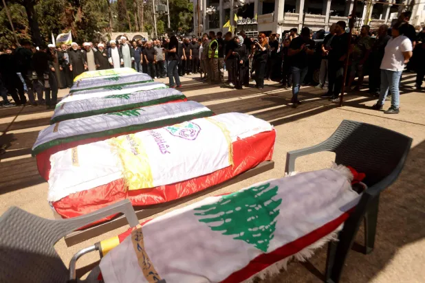 نعوش ملفوفة بالعلم اللبناني خلال تشييع 12 شخصاً قتلوا بغارة إسرائيلية في بلدة كفر رمان بجنوب لبنان الاثنين بينهم مقاتلين اثنين في «حزب الله» (أ.ف.ب)