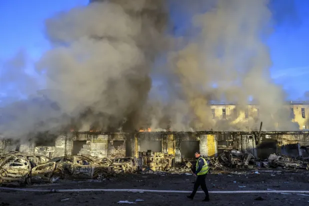 Ukrayna'nın Kiev kentinde Rus saldırısının gerçekleştiği bölgenin yakınında yürüyen bir polis, (EPA)
