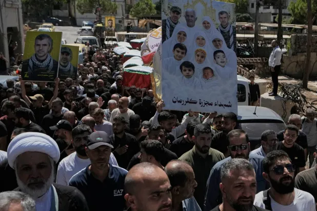 Mourners carry pictures of victims killed in an Israeli airstrike on Kafr Rumman in southern Lebanon during their funeral. (AP) 