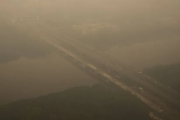 This aerial photo taken from a commercial aircraft shows haze from Indonesian forest fires blanketing a bridge in Kuching, the capital city of Malaysia's Sarawak state on the island of Borneo on September 5, 2026. (AFP)