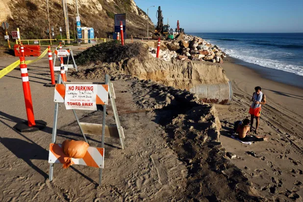 MALIBU, CALIFORNIA - SEPTEMBER 10: People gather near erosion damage along a beach access road to Point Dume, which remains closed due to the erosion from powerful surf and high tides earlier this summer, on September 10, 2026 in Malibu, California. Mario Tama/Getty Images/AFP 