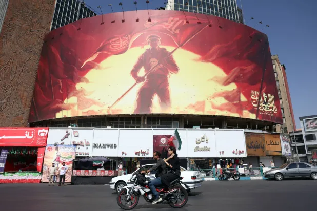 Iranians drive past a political billboard at the Valiasr square in central Tehran, Iran, 13 September 2026.  EPA/ABEDIN TAHERKENAREH 