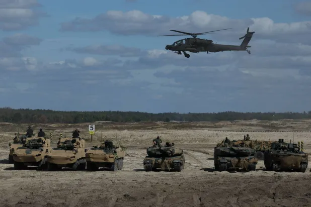 مروحية هجومية من طراز «أباتشي AH - 64» تابعة للجيش البولندي تحلّق فوق مركبات عسكرية وجنود خلال عرض تدريبي عسكري بميدان نوفا ديبا في كيلسي - بولندا 7 سبتمبر الحالي (رويترز)