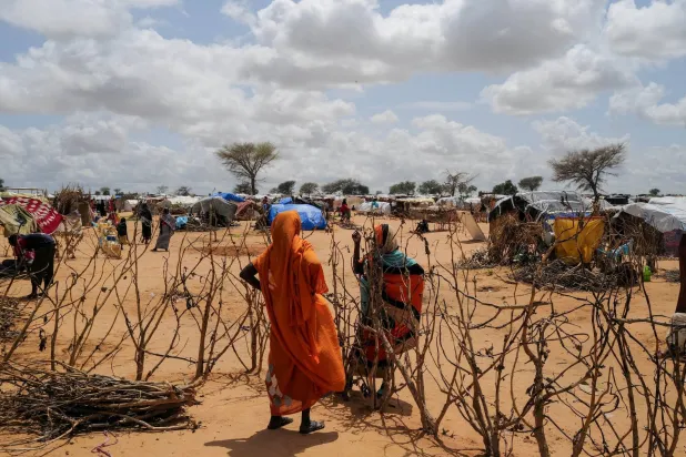 A Sudanese woman, who fled the conflict in Geneina in Sudan's Darfur region, talks to her relative through a fence next to makeshift shelters, in Adre, Chad August 5, 2023. (Reuters)