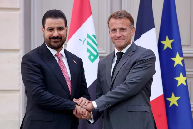 مصافحة بين الرئيس ماكرون ورئيس الوزراء العراقي علي الزيدي عقب مراسم التوقيع (أ.ف.ب)