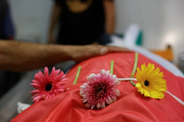 وُضعت زهور على جثمان رجل فلسطيني يبلغ من العمر 54 عاماً، قُتل على يد القوات الإسرائيلية خلال مداهمة، بينما كان المشيعون ينعونه في مستشفى بمدينة رام الله في الضفة الغربية (رويترز)