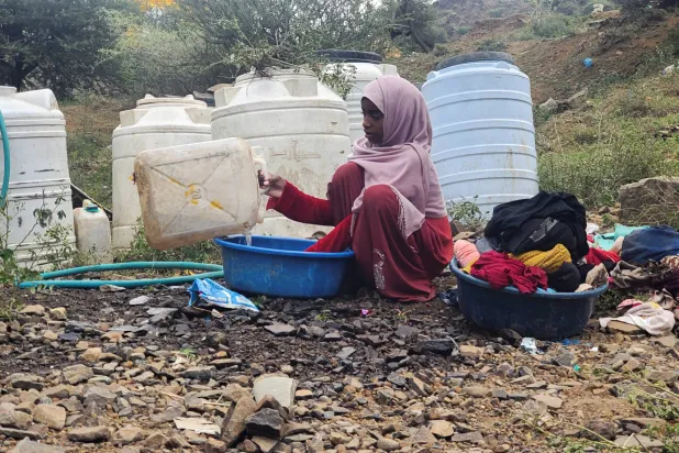 يمنية في تعز تغسل الملابس في مخيم مؤقت للنازحين جراء التصعيد الحوثي (رويترز)