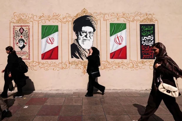 Iranians walk past a wall decorated with the image of assassinated Iranian supreme leader Ali Khamenei and the national flag, in central of Tehran on September 14, 2026. (AFP)