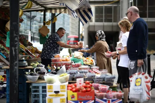 متسوّق يشتري الفواكه والخضراوات من إحدى بسطات البيع في وسط لندن ببريطانيا (رويترز)