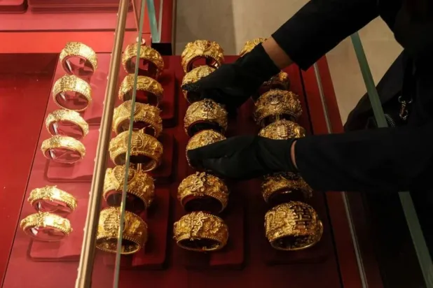 A shop attendant displays pairs of gold bracelets for Chinese weddings during a media preview of the Chow Tai Fook Jewellery Group flagship store soft opening, in Hong Kong, China, February 11, 2026. (Reuters)