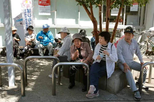 Elderly people rest under the shade of a tree in Tokyo, Sunday, Sept. 14, 2014. (AP)