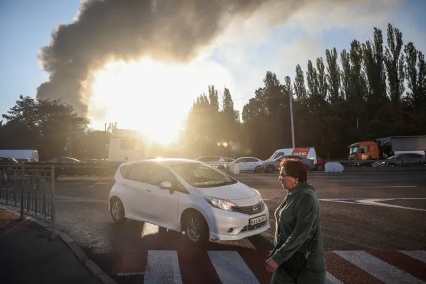  A woman crosses a road as smoke rises in the background from the site of a Russian drone strike, amid Russia’s attack on Ukraine, in Kyiv, Ukraine, September 16, 2026. (Reuters)