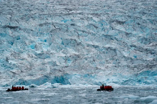 Two groups from the Poseidon Expeditions tour company look at a glacier in the Scoresby Sund, Sept. 7, 2023, in Greenland. (AP)