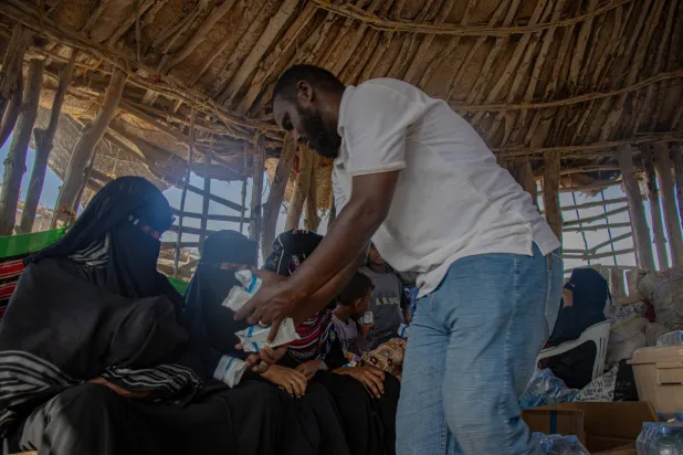 موظف من ”المنظمة الدولية للهجرة“ يستقبل فارين من الحرب الدائرة في اليمن في جيبوتي أمس (رويترز)
