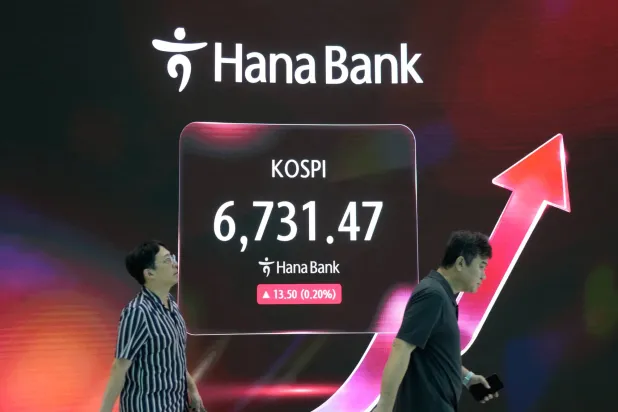 متداولون يمرون أمام شاشة تعرض مؤشر «كوسبي» في غرفة تداول العملات الأجنبية بمقر بنك «هانا» في سيول (أ.ب)