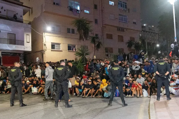 عناصر الشرطة خلال تأمين عملية نقل المهاجرين من شواطئ سبتة إلى مخيم في منطقة الميناء (رويترز)
