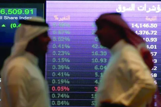 رجلان يتحدثان أمام إحدى شاشات الأسهم في السوق السعودية (رويترز)