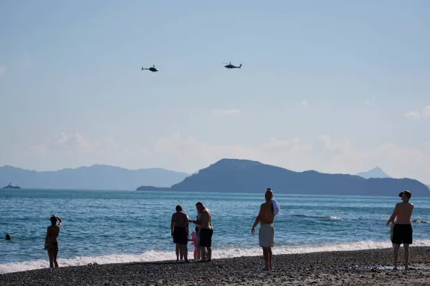 Tourists from a nearby hotel watch military helicopters fly overhead during Medusa 15, a joint military exercise led by Greece and Egypt, at Maleme on the Greek island of Crete, Friday, Sept. 18, 2026. (AP Photo/Thanassis Stavrakis)