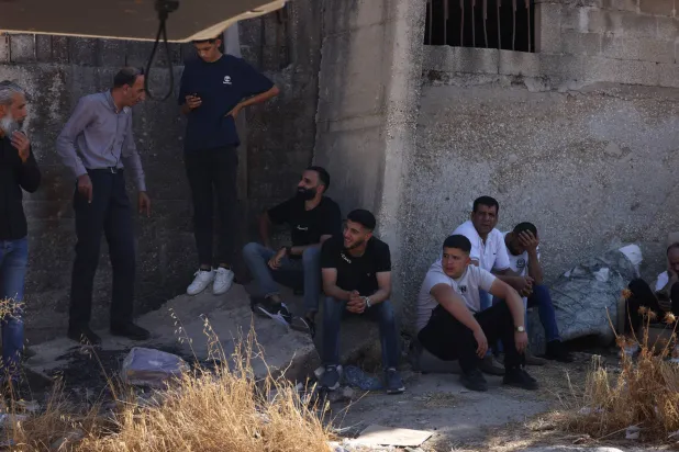 فلسطينيون ينتظرون عبور حاجز عسكري شرق نابلس بالضفة الغربية أمس (إ.ب.أ)