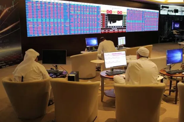 مستثمرون في قطر يتابعون أسعار الأسهم على شاشة التداول ببورصة الدوحة (رويترز)