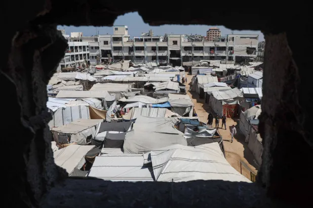 Displaced Palestinians walk through a tent camp inside a school-turned-shelter in Khan Younis, in the southern Gaza Strip, September 10, 2026. (Reuters)