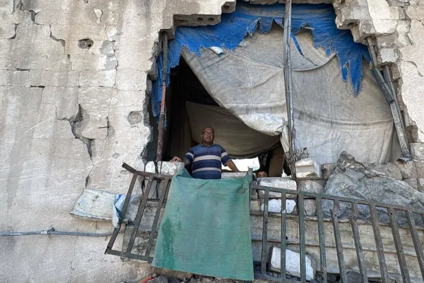 Palestinian Bassam Nusseir, a displaced person in Gaza City, stands amidst the rubble of a collapsed building housing him and his family (Asharq Al-Awsat)