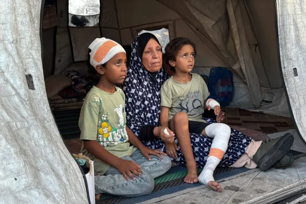Palestinian Umm Iyad Azzam sits with her two grandchildren who survived the collapse of the Al-Saada building in Gaza (Asharq Al-Awsat) 
