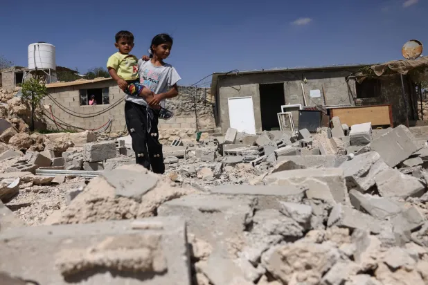 طفلان فلسطينيان يقفان وسط أنقاض منزل هدمته القوات الإسرائيلية في قرية «جنبا» بالضفة الغربية المحتلة الأربعاء (أ.ف.ب)