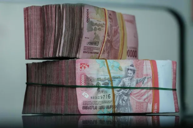 أوراق نقدية من الروبية الإندونيسية مُكدّسة في مكتب لصرافة العملات في جاكرتا (أ.ف.ب)