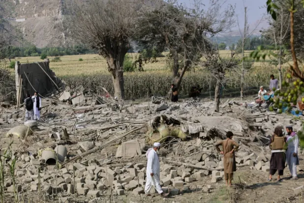 Doğu Afganistan’ın Kunar vilayetindeki Patan köyünde, hava saldırısında yıkılan bir evin enkazını inceleyen bölge sakinleri (AP)