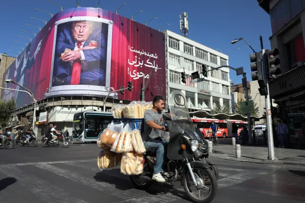  إيراني يقود دراجته النارية أمام لوحة دعائية مناهضة للرئيس الأميركي دونالد ترمب في طهران الأسبوع الماضي (إ.ب.أ)
