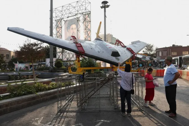 Tahran sokaklarından birinde, İran’ın dini lideri Mücteba Hamaney’in fotoğrafının yer aldığı bir panonun yanında sergilenen İran yapımı insansız hava aracı, (Reuters)