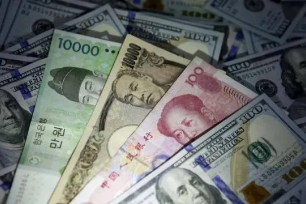 أوراق نقدية من الوون الكوري الجنوبي واليوان الصيني والين الياباني على أوراق نقدية من فئة 100 دولار أميركي (رويترز)