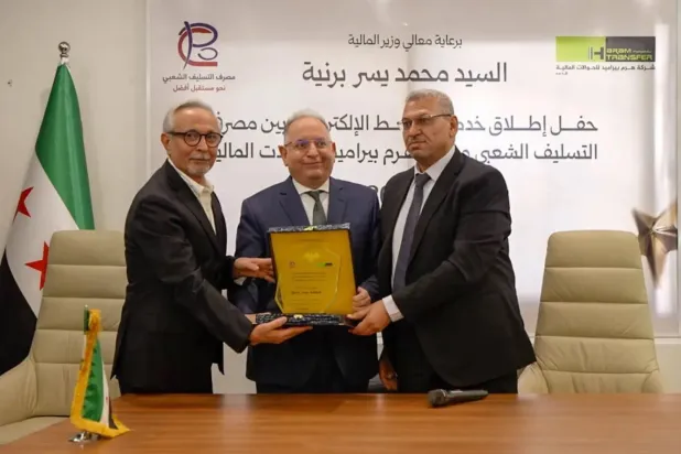Syrian Finance Minister Mohammed Yisr Barnieh participates in the launch of an electronic link between the Popular Credit Bank and Al-Haram Transfer Company (minister’s account)