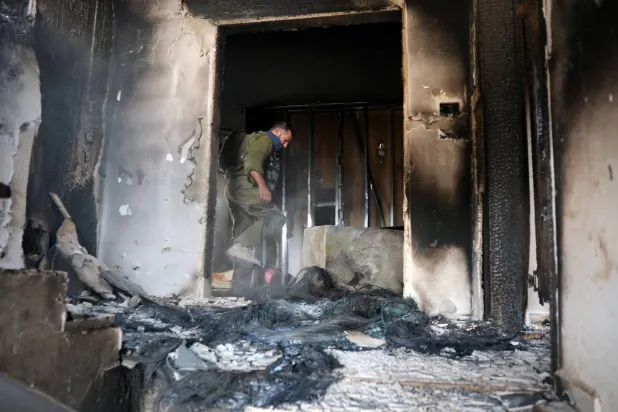 جندي إسرائيلي داخل منزل مملوك لفلسطينيين في الضفة الغربية بعد تعرضه لهجوم وإحراقه من قبل مستوطنين إسرائيليين يوم الثلاثاء (رويترز)
