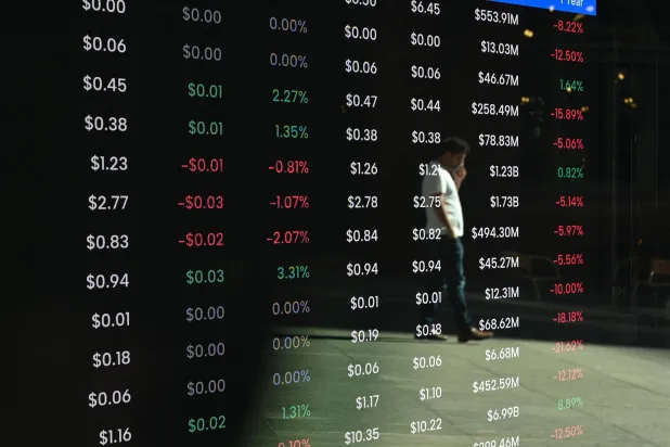 يظهر انعكاس أحد المارة على شاشة عرض أسعار الأسهم في مبنى بورصة سيدني للأوراق المالية (أ.ف.ب)