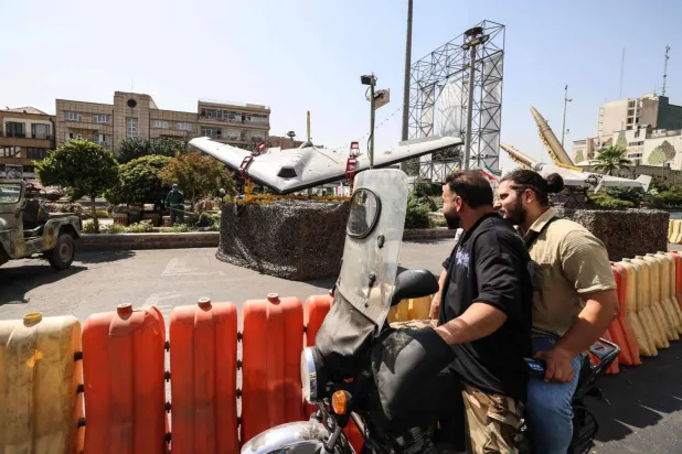Tahran’daki Baharistan Meydanı’nda sergilenen askeri insansız hava araçlarının yanından geçen bisikletliler (AFP)