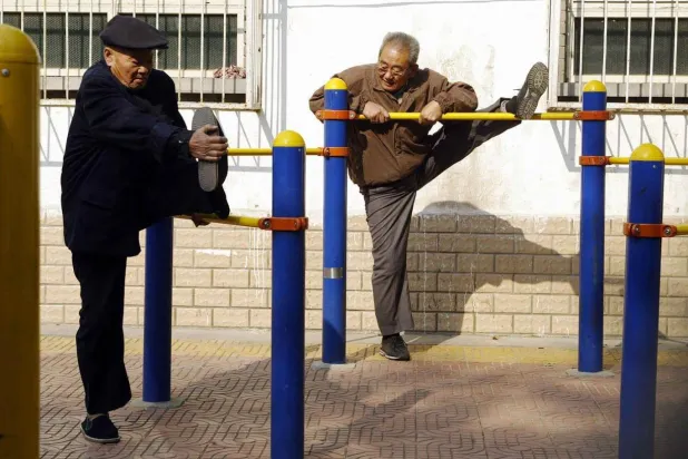 Pekin’deki bir parkta Çinli yaşlı erkekler esneme egzersizleri yapıyor (AFP)