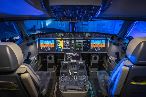 صورة توضح البنية الهندسية لقمرات القيادة الحديثة (Glass Cockpits) حيث تنتشر الشاشات الرقمية المتقدمة، وتظهر لوحة التحكم المركزية (Center Pedestal) الواقعة بين مقعدي القبطان والمساعد. في هذه المنطقة تحديداً، يتواجد جهاز الإرسال والاستقبال (Transponder) الذي يستخدمه الطيارون لطباعة رموز الطوارئ الثلاثية (7700، 7600، 7500) لتظهر فوراً على رادارات المراقبين الأرضيين (ويكيبيديا)