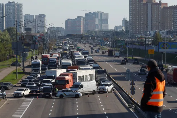 A construction worker looks at vehicles stuck in a traffic jam near the bridge caused by the overnight jet drone strikes on Kyiv's bridges, amid Russia's attack on Ukraine, in Kyiv, Ukraine October 2, 2026.  REUTERS/Valentyn Ogirenko