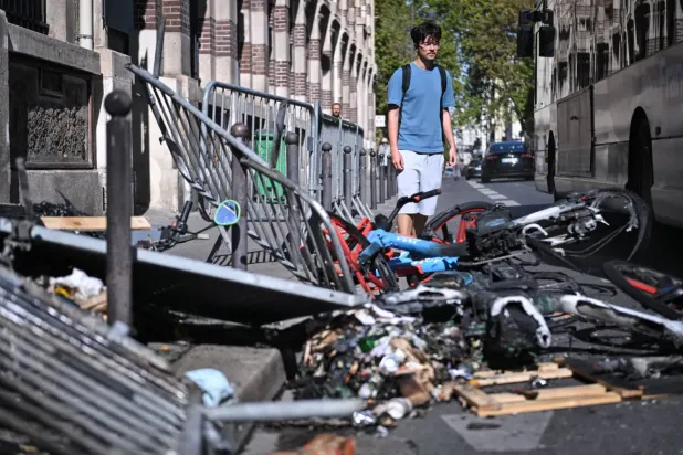 Paris’te lise öğrencilerinin düzenlediği protesto sırasında polis ile göstericiler arasında çıkan çatışmaların ardından bölgede meydana gelen yıkımın izleri önünden geçen bir kişi (EPA)