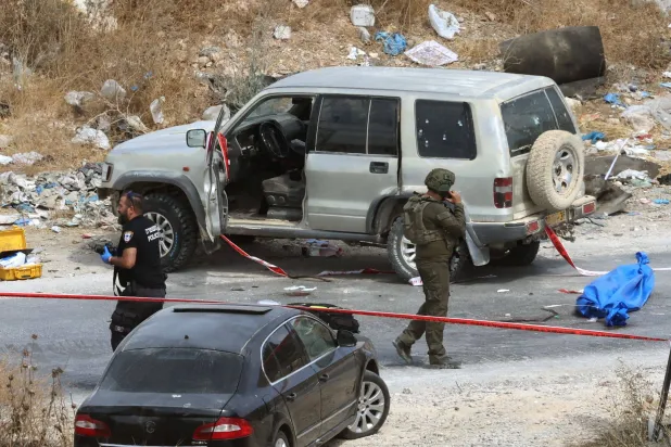 A blue body bag containing the body of a Palestinian man shot by Israeli forces in an incident in which a car hit a military jeep, is guarded as it lies on the road close to the Israeli-occupied West Bank town of Bani Naim on October 5, 2026. (Photo by Ahmad GHARABLI / AFP)