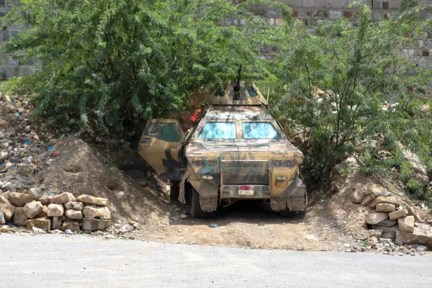 An armored vehicle belonging to the Yemeni government forces is stationed under a tree near to the Jabal Han front west of the city of Taiz following fierce battles with the Houthis on October 3, 2026. (AFP) 