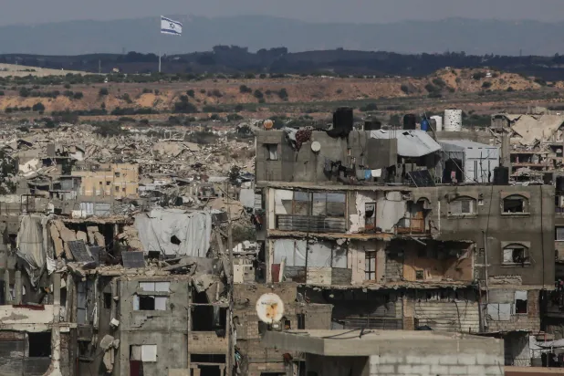 A photograph shows destruction at the Jabalia refugee camp in the northern Gaza Strip, with an Israeli flag fluttering in the background, on October 5, 2026. (AFP)