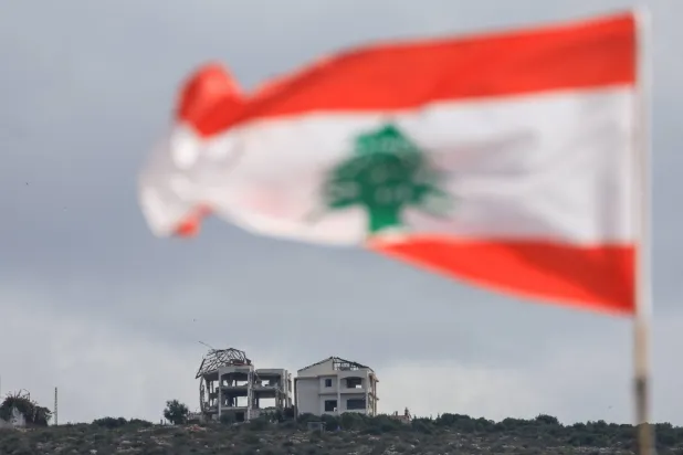A Lebanese flag flies as buildings lie in ruins in Mansouri, as seen from Henniye, Lebanon, September 29, 2026. (Reuters)