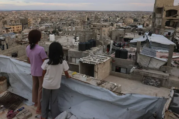أطفال فلسطينيون يقفون أعلى سطح في مخيم جباليا شمال قطاع غزة أمس (أ.ف.ب)
